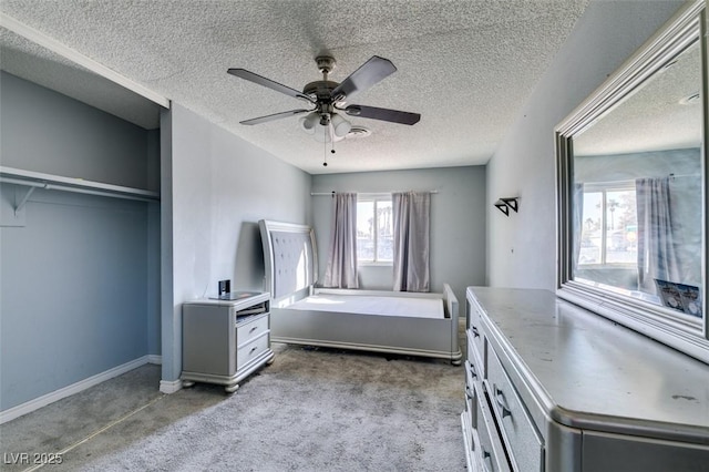 unfurnished bedroom with ceiling fan, carpet floors, a textured ceiling, and baseboards