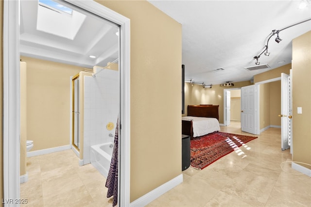 hallway with a skylight, light tile patterned floors, baseboards, visible vents, and rail lighting