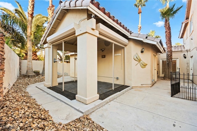 back of house with a fenced backyard, a tile roof, a patio, and stucco siding