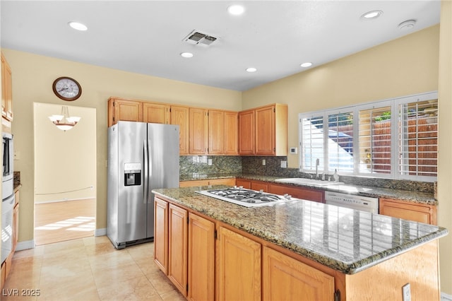 kitchen with white appliances, a sink, a kitchen island, dark stone counters, and tasteful backsplash