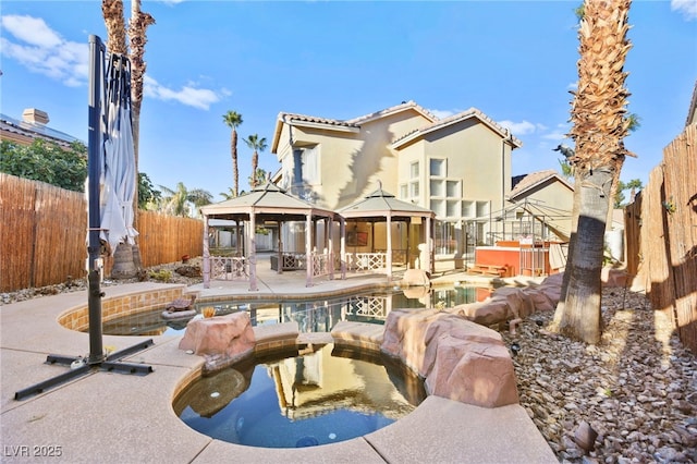 rear view of property with a gazebo, a fenced backyard, a fenced in pool, and an in ground hot tub