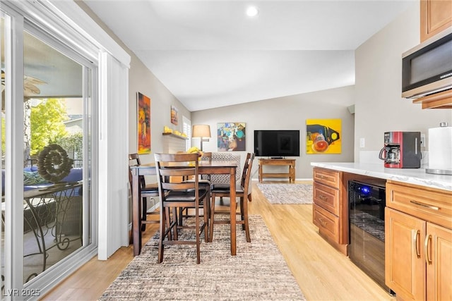 dining space featuring light wood-style floors, recessed lighting, beverage cooler, and vaulted ceiling