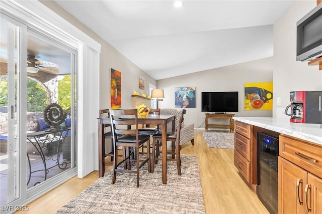 dining area with beverage cooler, vaulted ceiling, and light wood finished floors