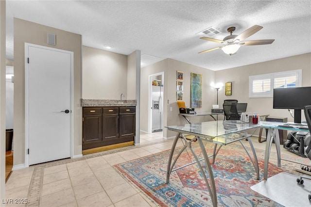 office featuring baseboards, visible vents, a ceiling fan, a textured ceiling, and light tile patterned flooring