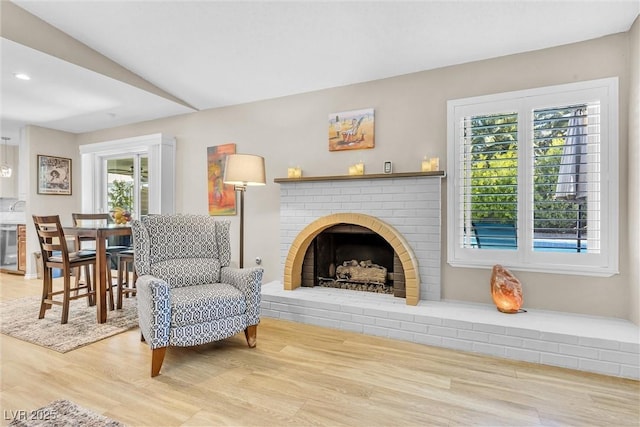 living area featuring beverage cooler, a fireplace, and wood finished floors