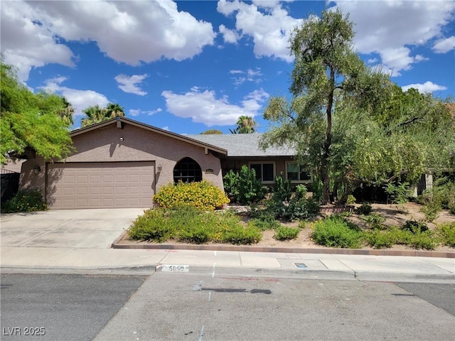 single story home with a garage, concrete driveway, and stucco siding