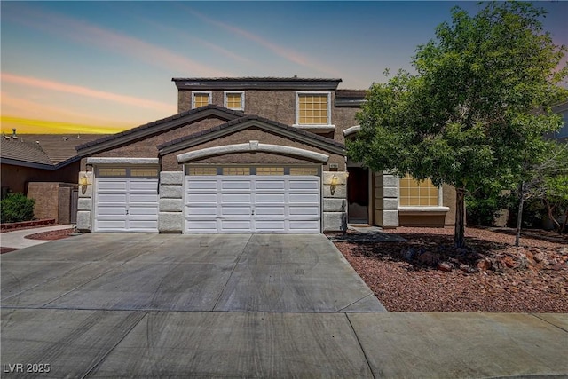 traditional home featuring stone siding, driveway, and an attached garage