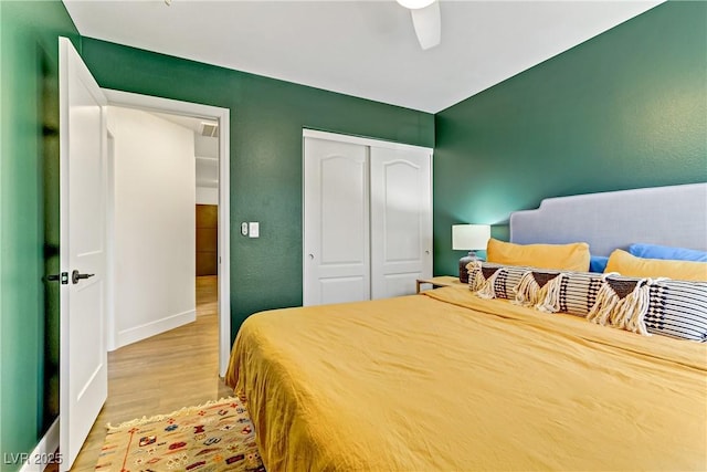 bedroom featuring baseboards, a closet, light wood-style flooring, and a ceiling fan