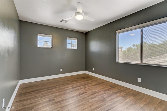 spare room featuring ceiling fan, wood finished floors, visible vents, and baseboards