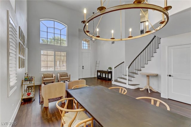 dining room with dark wood-style floors, a high ceiling, baseboards, and stairs