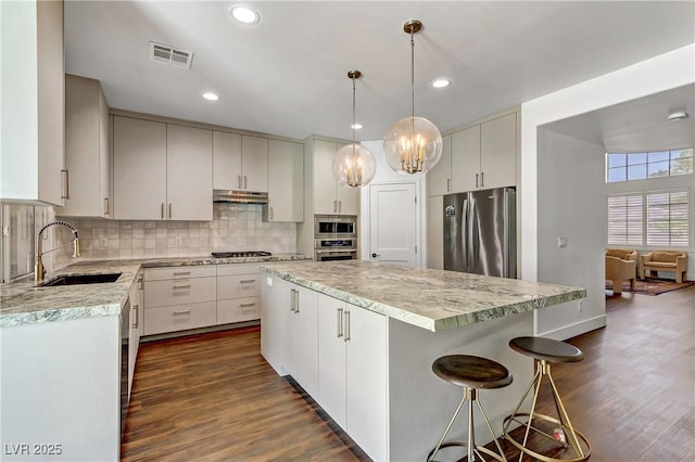 kitchen featuring appliances with stainless steel finishes, white cabinetry, visible vents, and a center island