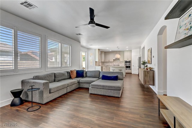 living room with dark wood-style floors, ceiling fan, and visible vents