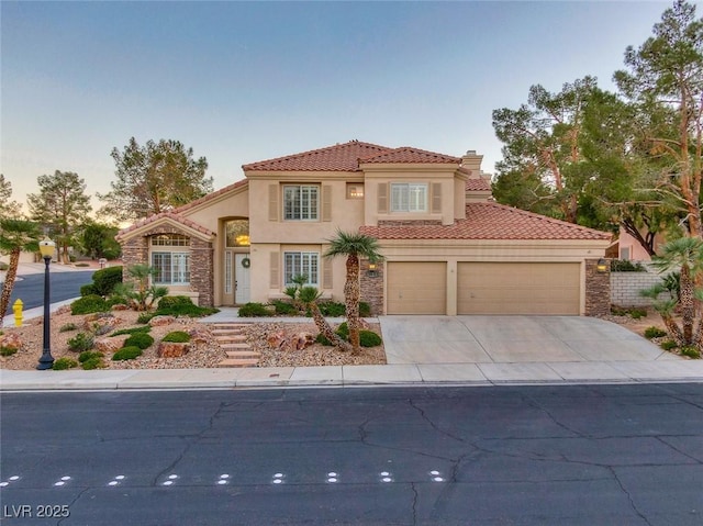 mediterranean / spanish home featuring a garage, concrete driveway, stone siding, a tiled roof, and stucco siding