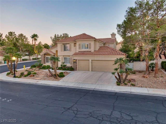 mediterranean / spanish home featuring a tile roof, stucco siding, concrete driveway, an attached garage, and fence