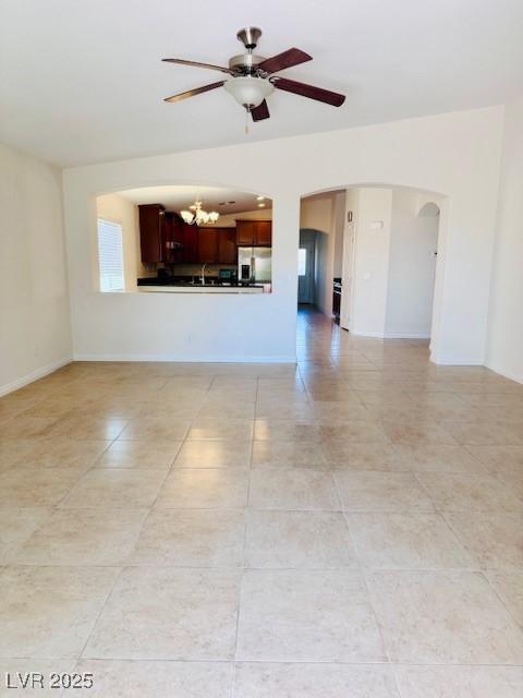 4562 White Cap Mill St, Las Vegas, NV 89147 - unfurnished living room with a chandelier, light tile patterned floors, a ceiling fan, arched walkways, and baseboards