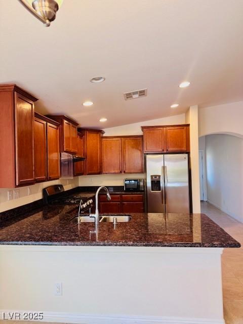 4562 White Cap Mill St, Las Vegas, NV 89147 - kitchen featuring stainless steel refrigerator with ice dispenser, a peninsula, a sink, arched walkways, and dark stone counters