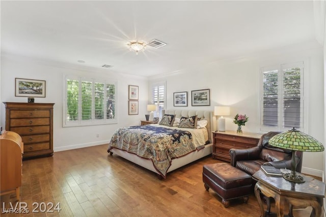 bedroom featuring visible vents, baseboards, and wood finished floors