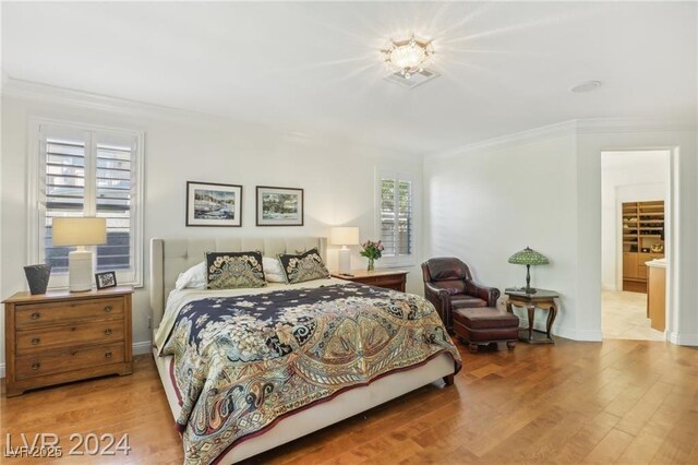 bedroom with ornamental molding, light wood-style flooring, and baseboards