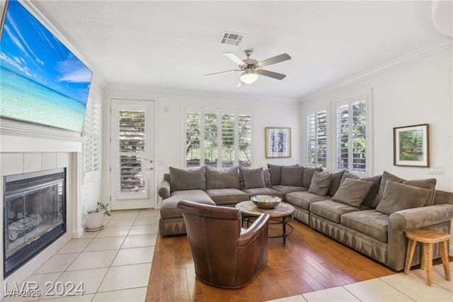 living room featuring a healthy amount of sunlight, a fireplace, visible vents, and ornamental molding