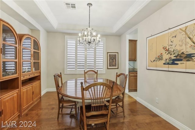 dining room featuring dark wood-type flooring, a tray ceiling, visible vents, and baseboards