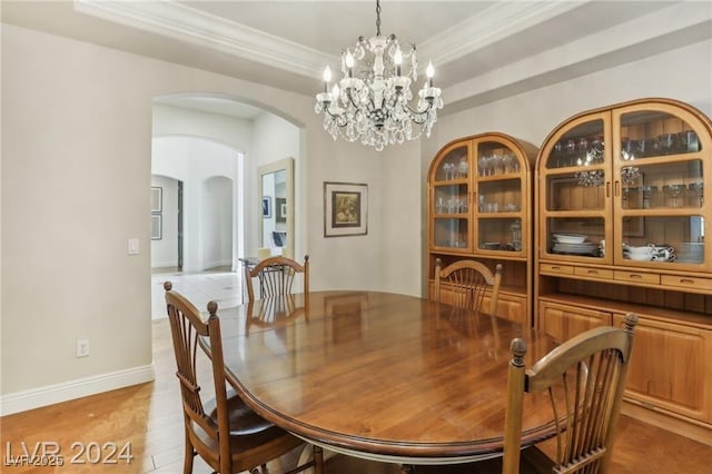 dining room with baseboards, arched walkways, a raised ceiling, ornamental molding, and a chandelier