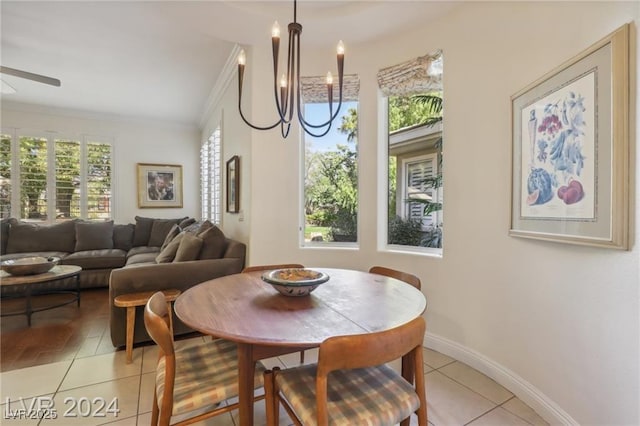 dining area featuring light tile patterned flooring, crown molding, baseboards, and ceiling fan with notable chandelier