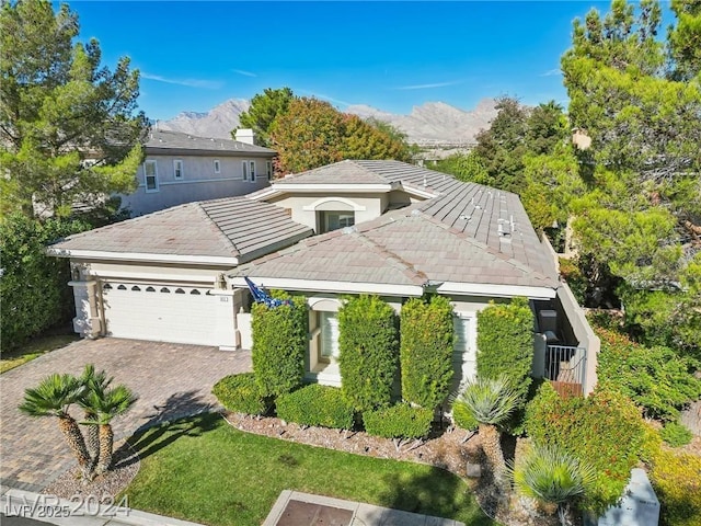 view of front of property with an attached garage, a mountain view, decorative driveway, and a tiled roof