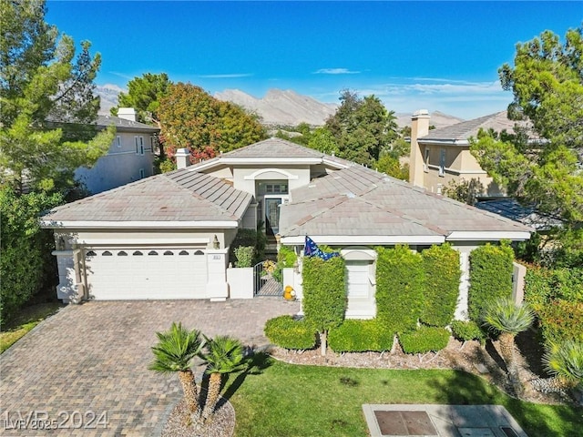 view of front facade featuring a garage, fence, a mountain view, and decorative driveway