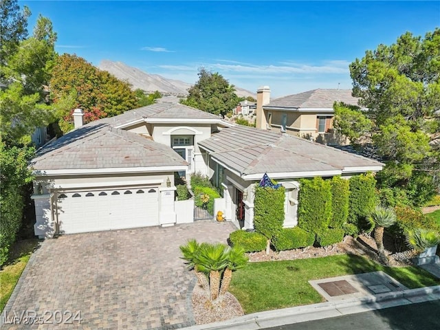 view of front facade featuring an attached garage, a mountain view, and decorative driveway