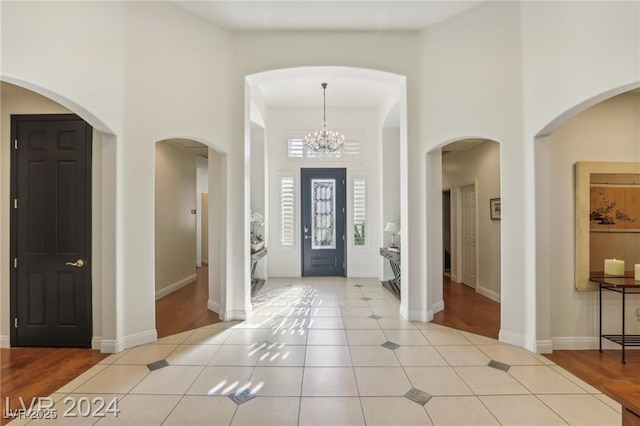 entryway featuring light tile patterned floors, a high ceiling, and baseboards
