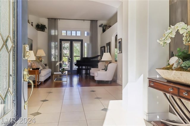 foyer with arched walkways, french doors, and tile patterned floors