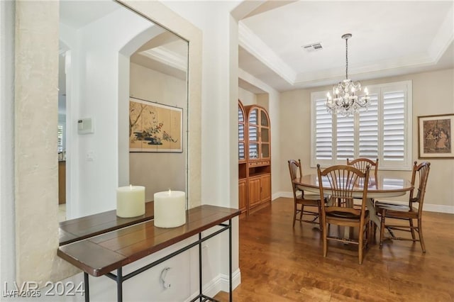 dining space featuring arched walkways, visible vents, a raised ceiling, dark wood-style floors, and a notable chandelier