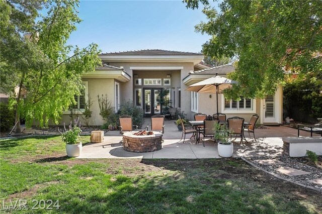 back of property with french doors, stucco siding, a lawn, a patio area, and a fire pit