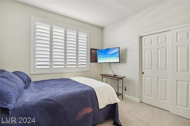 bedroom featuring a closet, light carpet, and baseboards