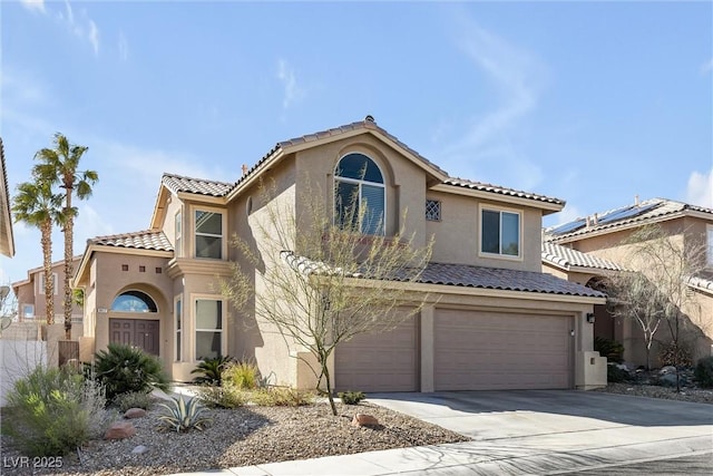 mediterranean / spanish home with concrete driveway, a tile roof, an attached garage, and stucco siding