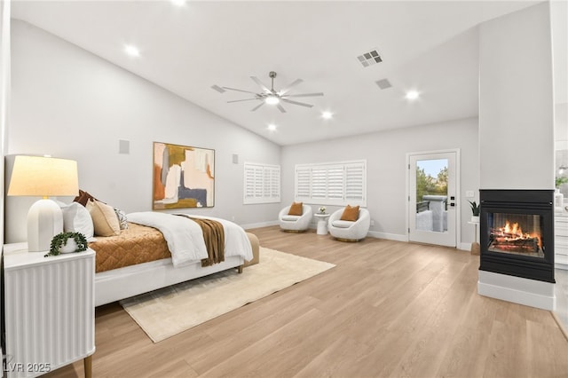 bedroom featuring access to exterior, light wood-style flooring, visible vents, and a multi sided fireplace