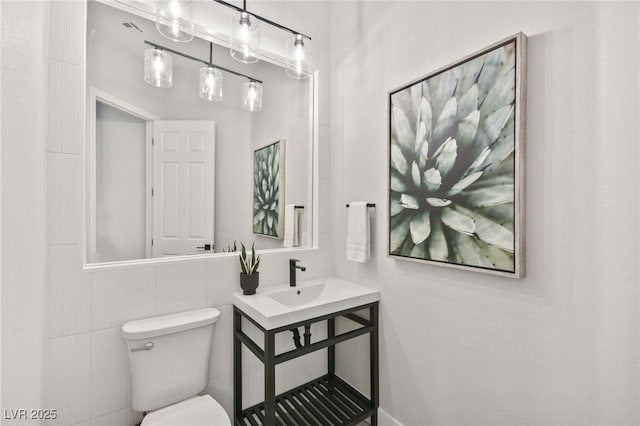 half bath featuring toilet, visible vents, and a sink