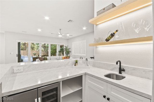 kitchen with open shelves, visible vents, white cabinetry, a sink, and light stone countertops