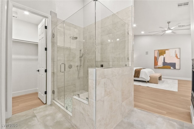 ensuite bathroom featuring a walk in closet, visible vents, ceiling fan, a shower stall, and ensuite bath