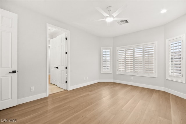 spare room with light wood finished floors, baseboards, visible vents, and ceiling fan