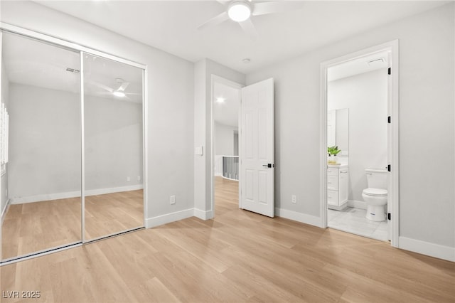 unfurnished bedroom with a closet, light wood-style flooring, ceiling fan, ensuite bath, and baseboards