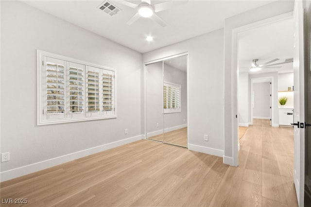 unfurnished bedroom with a closet, visible vents, ceiling fan, light wood-type flooring, and baseboards