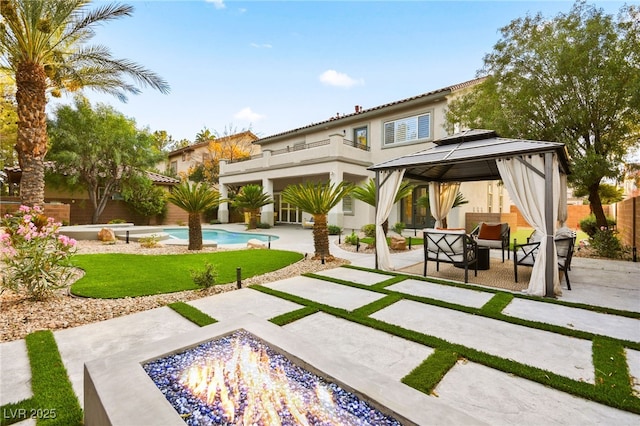 rear view of property with a fenced in pool, stucco siding, a gazebo, a patio area, and fence