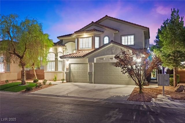 mediterranean / spanish house with concrete driveway, a tile roof, an attached garage, and stucco siding