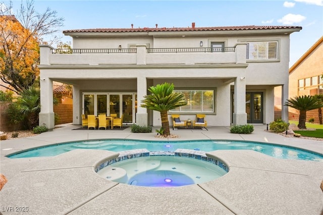 rear view of house featuring a patio area, a balcony, and stucco siding