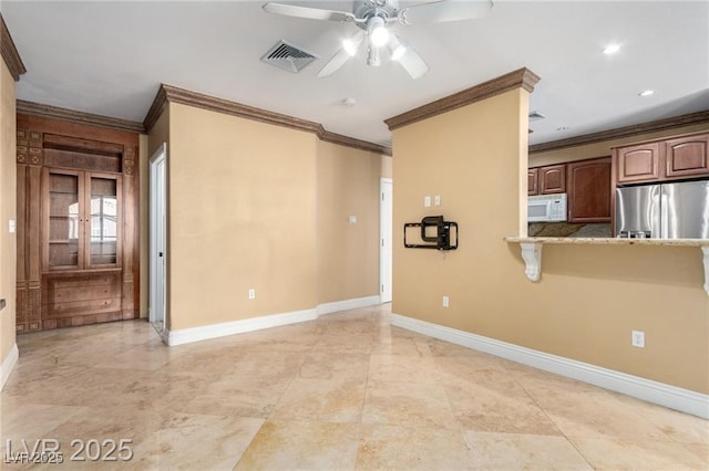 empty room with crown molding, ceiling fan, visible vents, and baseboards