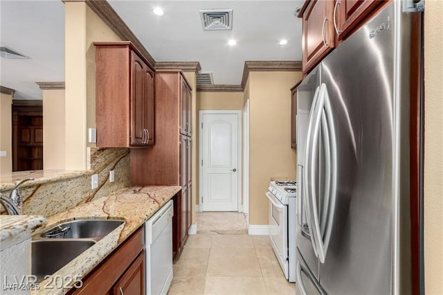 kitchen featuring white appliances, visible vents, light stone counters, ornamental molding, and a sink