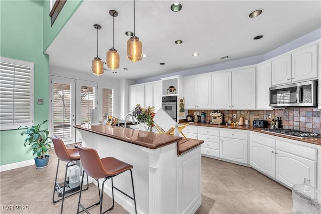 kitchen with decorative backsplash, dark countertops, a kitchen breakfast bar, and appliances with stainless steel finishes