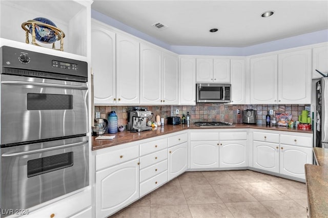 kitchen featuring tasteful backsplash, visible vents, stainless steel appliances, and dark countertops