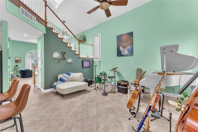 tiled living room featuring visible vents, a ceiling fan, stairway, a high ceiling, and baseboards